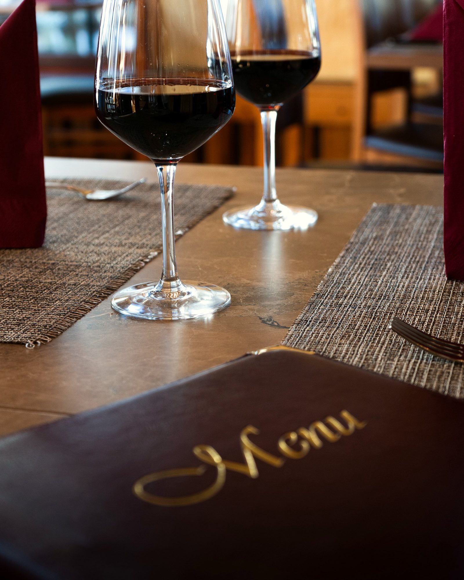 Le livret de la carte et deux verres de vin rouge sur une table du Grotto